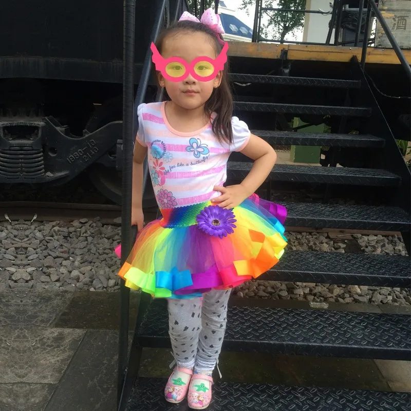 tüdruk kannab vikerkaare värvilist kohevat seelikut ja roosasid prille