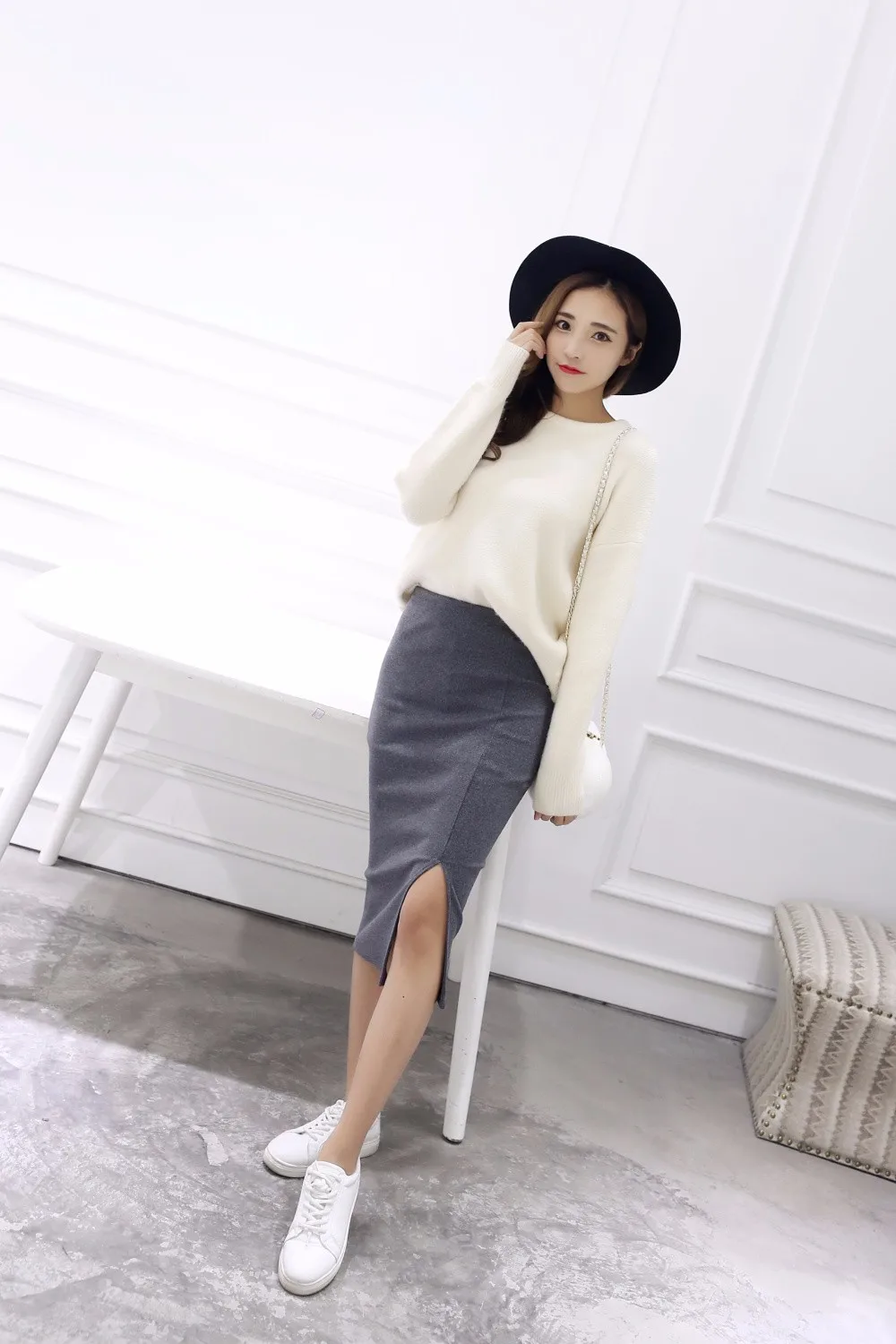 naine kannab halli pliiatsseelikut ja heledat kampsunit