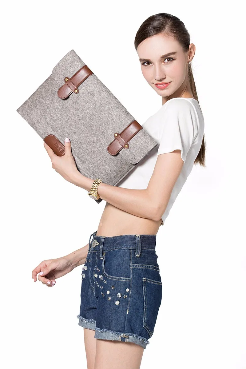 naine hoiab halli vildist sülearvutikotti pruuni nahast detailidega