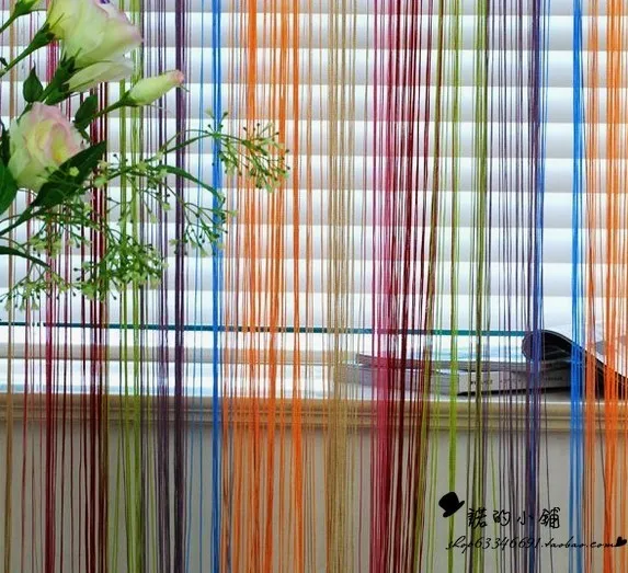 värviline nöörkardin akna ees, taustal lilledega vaas