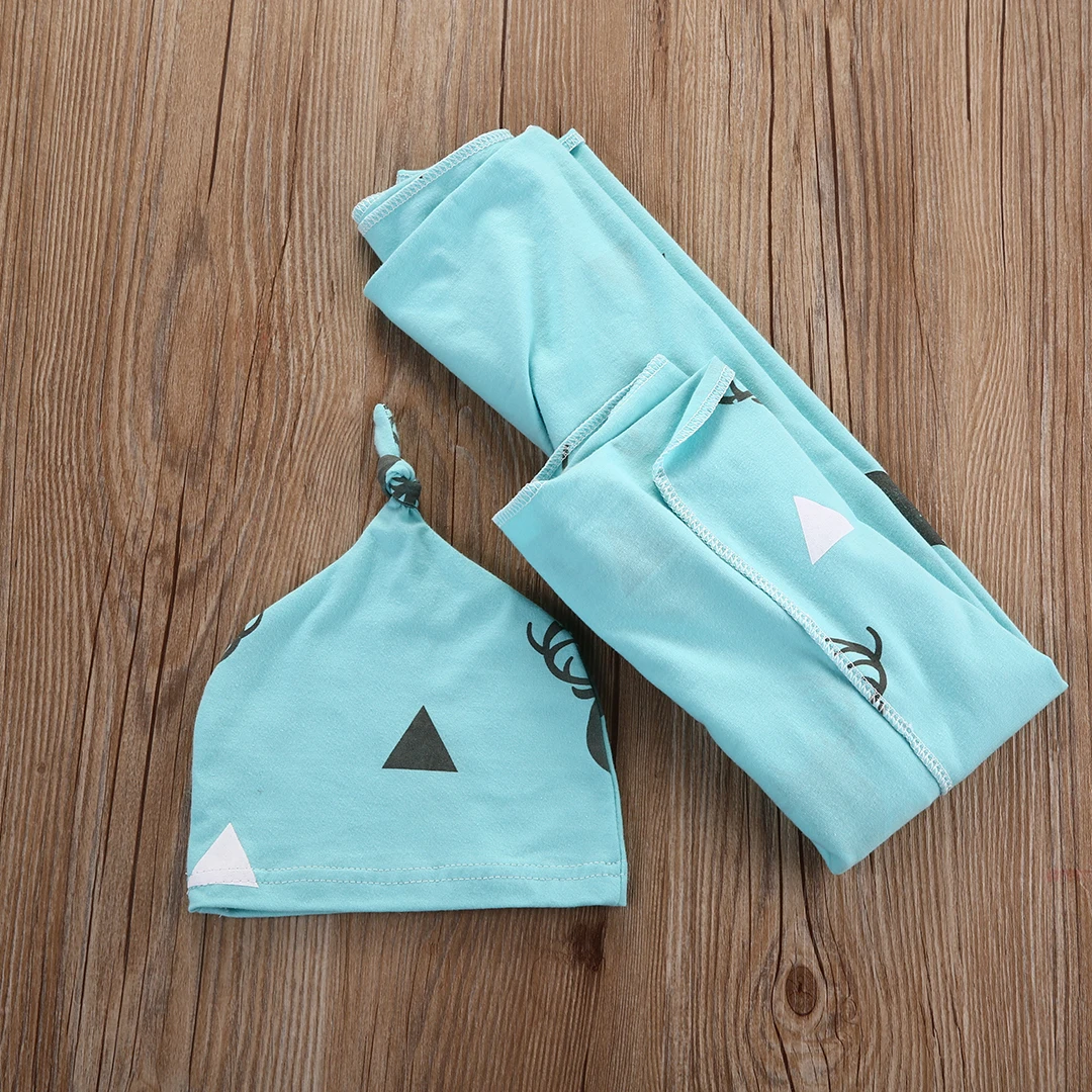 helesinine puuvillast beebitekk ja müts puidust taustal