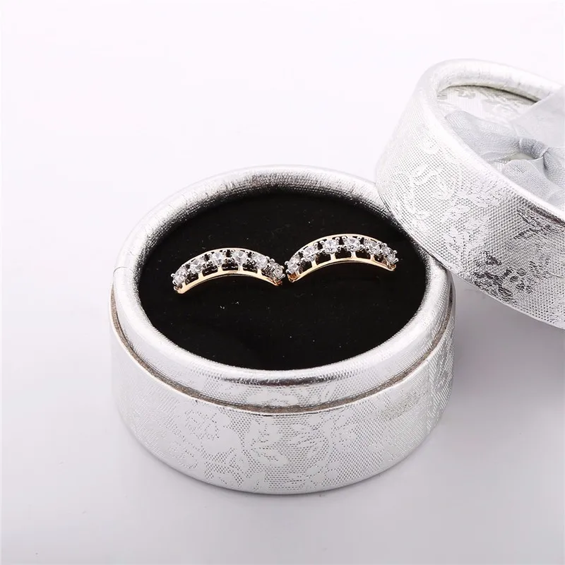 kuldse tooniga kõrvarõngad, millel on rida säravaid kivikesi, asetatud musta sametiga vooderdatud karpi