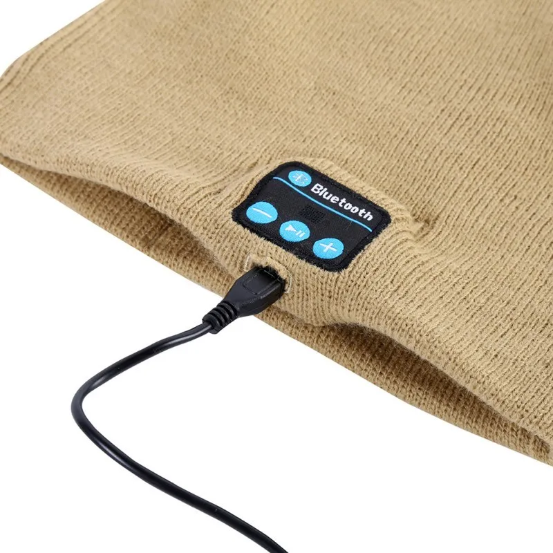 beež Bluetooth-funktsiooniga kootud müts, millel on juhtnupud ja laadimiskaabel