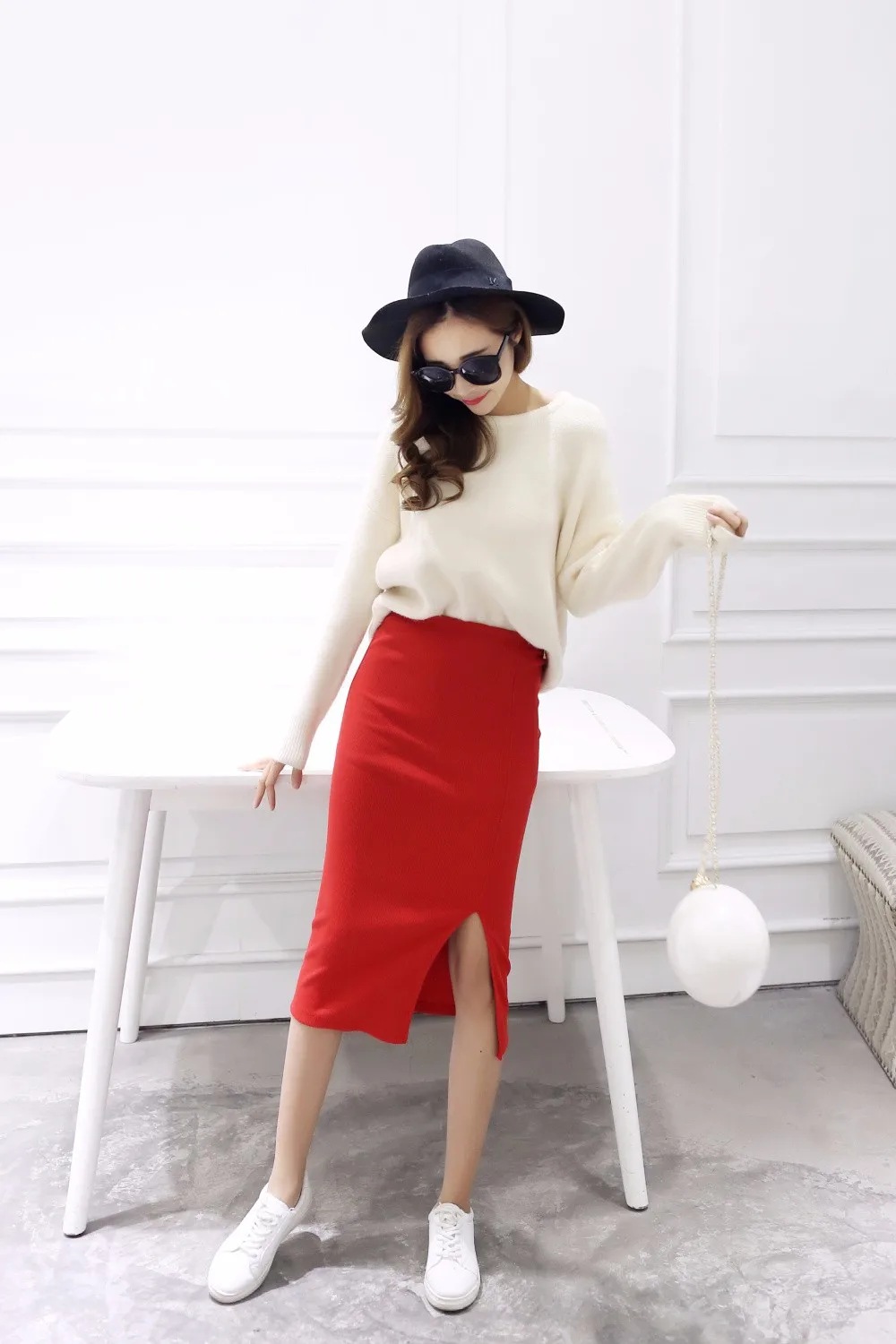 naine kannab punast pliiatsseelikut ja valget kampsunit