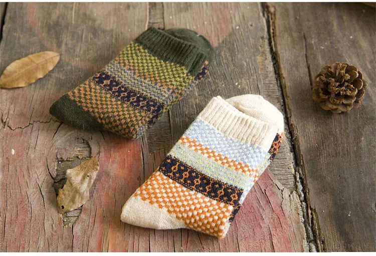kaks paari mustrilisi villaseid sokke puidust pinnal, üks paar rohelistes toonides ja teine heledates toonides