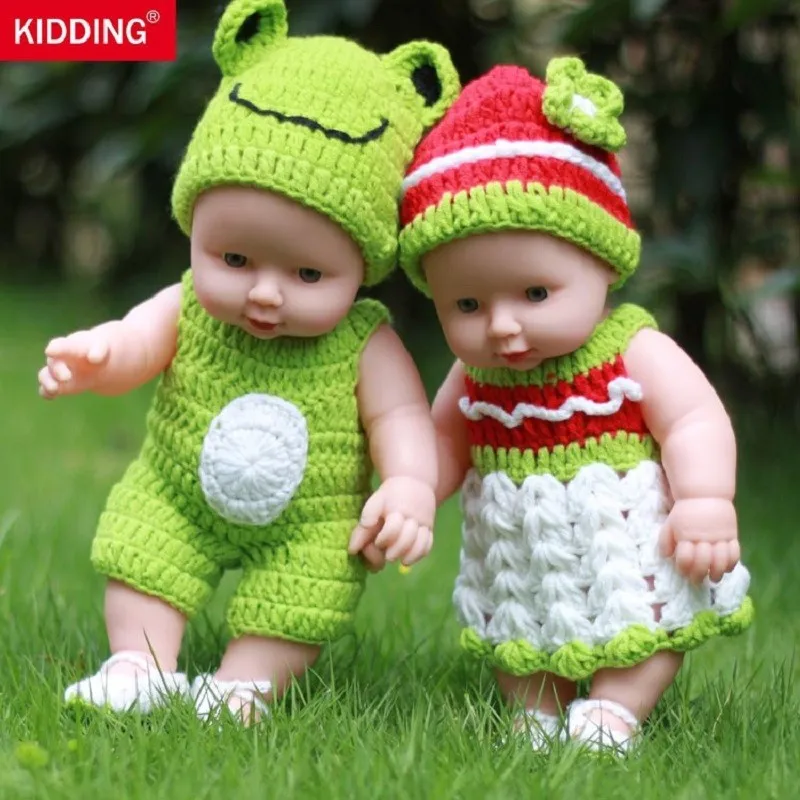 kaks kootud riietes nukku rohelisel murul, üks konnamütsiga ja teine lillemustriga kleidis