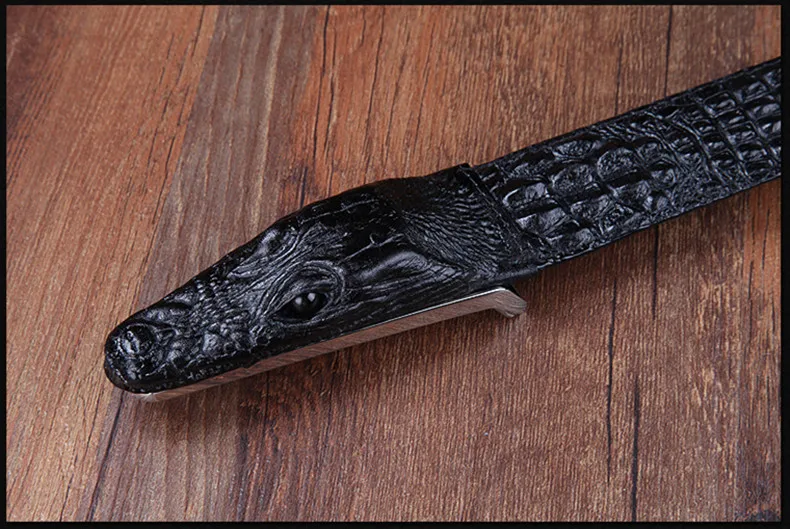 must krokodilli peaga nahast püksirihm puidust pinnal