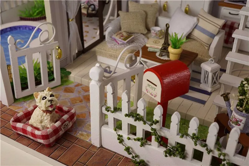 miniatuurne nukumaja koos mööbli ja aiaga, kus on punane postkast ja koer korvis
