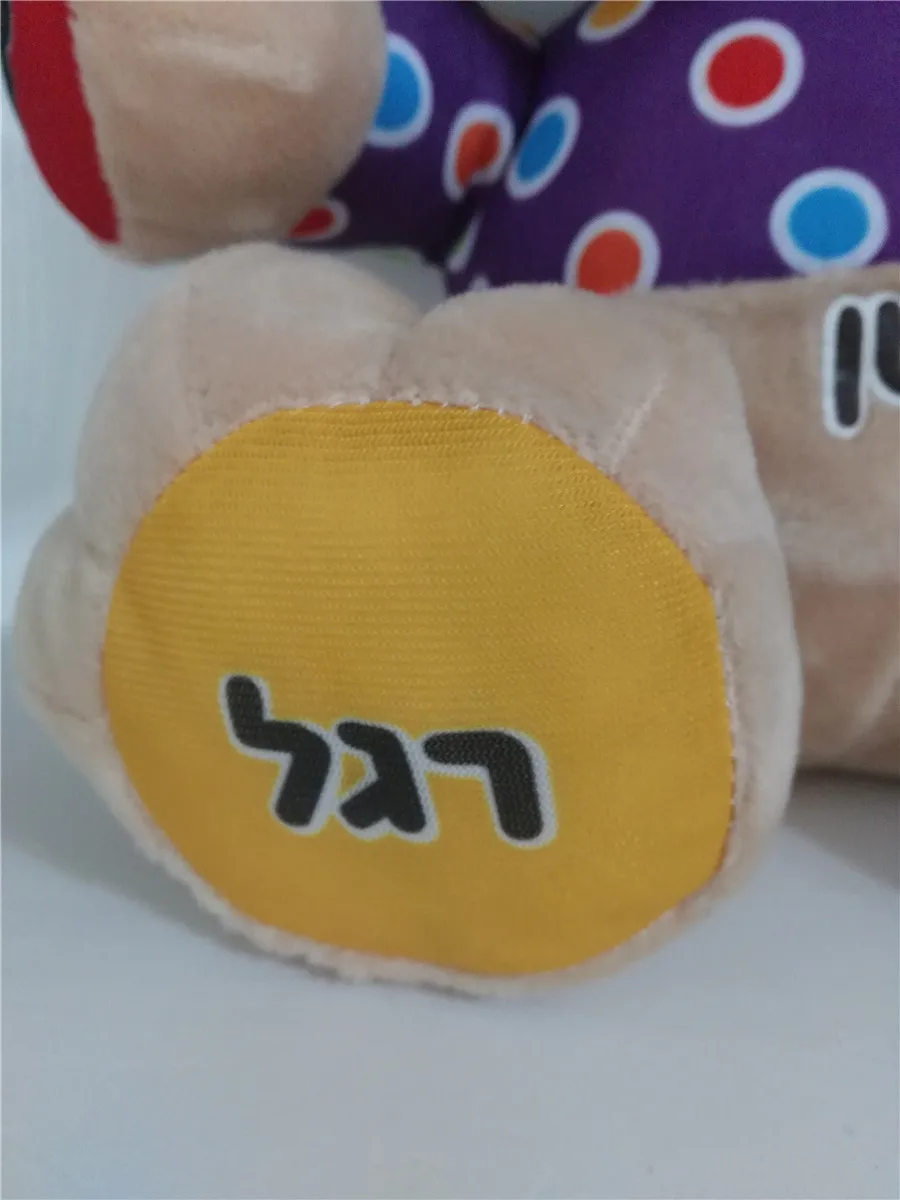 pehme koer, millel on värviliste täppidega lilla keha ja heebreakeelne tekst jalal