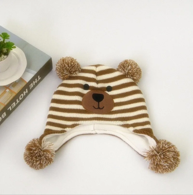 pruunide ja valgete triipudega laste müts, millel on karu nägu ja kõrvad