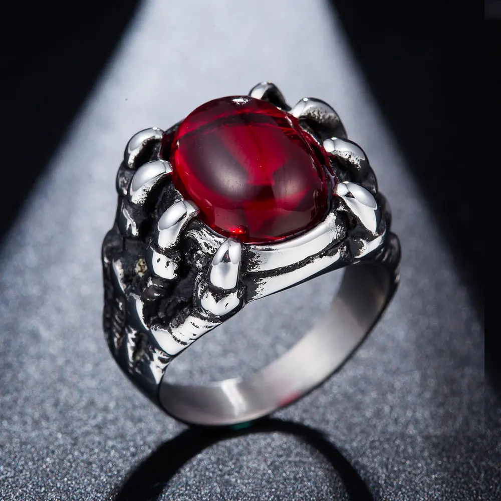 hõbedane sõrmus punase kiviga, mida ümbritsevad lohe küünised