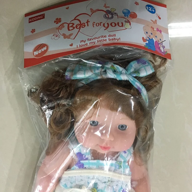 pakendis pruunide juustega nukk, millel on sinine lips ja lilleline kleit