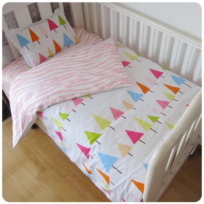 värviliste kolmnurkade ja roosade triipudega laste voodipesukomplekt valgel voodil