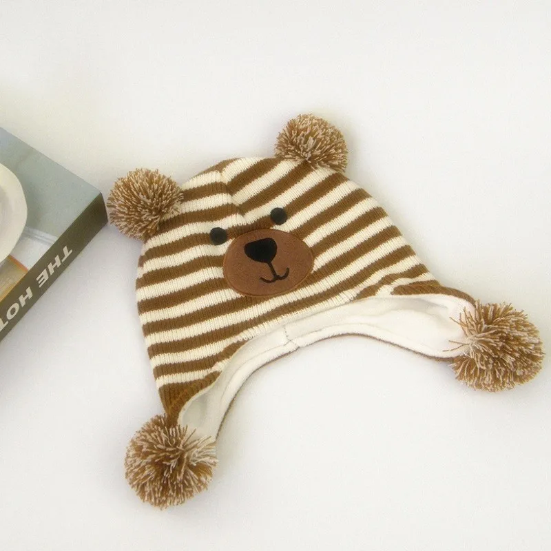 pruunide ja valgete triipudega laste müts, millel on karu nägu ja kõrvad