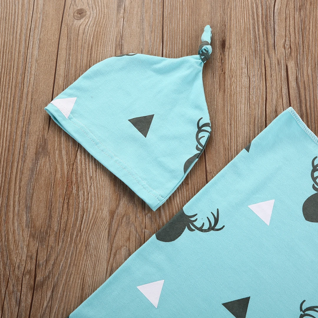 sinine puuvillast beebitekk ja müts puidust taustal, millel on geomeetrilised mustrid