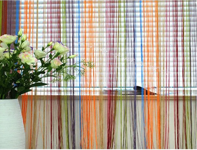 värviline nöörkardin akna ees, taustal lillevaas